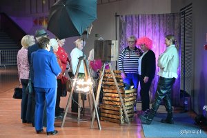 Wnętrze Polsat Plus Areny Gdynia, stoisko fotobudki, aparat i lampy na statywie, grupa osób, dwie osoby pozują do zdjęcia