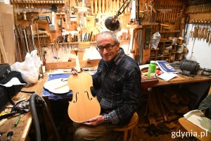 Pan Tomasz Grzeszczak, lutnik i opiekun szkolnych instrumentów trzyma w rękach skrzypce