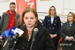 Kobieta mówiąca do kilku ustawionych obok siebie mikrofonów