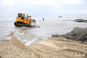 Spychacz jeździ po plaży.