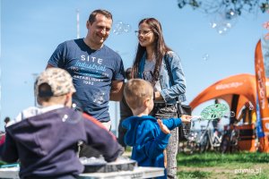 Para z dwójką dzieci na pikniku. Maluchy puszczają bańki mydlane