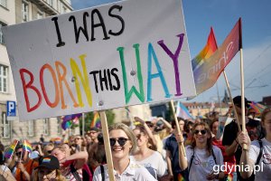 Grupa osób z tęczowymi flagami i transparentami
