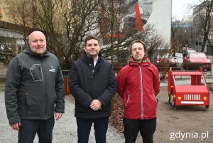 Trzej mężczyźni stojący w parku i patrzący w kierunku obiektywu
