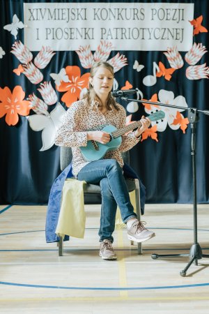Dziewczynka z gitarą na scenie podczas Miejskiego Konkursu Poezji i Piosenki Patriotycznej