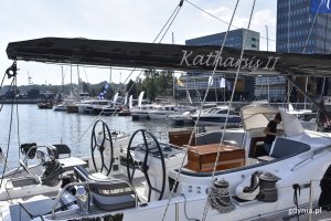 Biały jacht Katharsis II zacumowany przy kei w Marina Yacht Parku w Gdyni. Ma czarny maszt z wypisaną srebrnymi literami nazwą jednostki. W tle inne jachty // fot. Magdalena Czernek