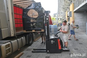 Mężczyzna na sztaplarce ładuje do ciężarówki paczki z pomocą dla Chersonia