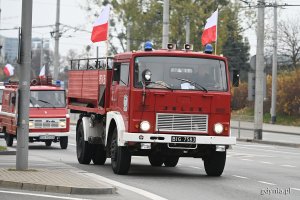 Czerwona ciężarówka strażacka przystrojona biało-czerwonymi flagami // fot. Michał Puszczewicz
