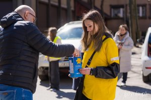 Młoda kobieta ze skarbonką i mężczyzna w czarnej kurtce