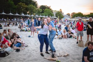 Ludzie bawią się na plaży podczas koncertu.