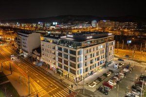 Nocne zdjęcie budynków, w których są zgaszone światła, stojących przy oświetlonych ulicach