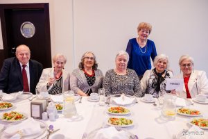 Grupa senior&oacute;w siedzi przy elegancko zastawionym stole