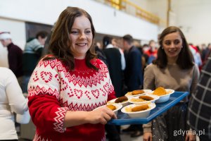 Prezydent Gdyni Aleksandra Kosiorek roznosząca świąteczne potrawy gościom wigilii dla samotnych i potrzebujących 