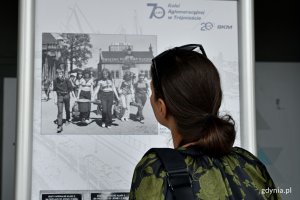 Kobieta stojąca przed jedną z tablic i oglądająca wystawę z okazji 70-lecia Kolei Aglomeracyjnej w Trójmieście oraz 20-lecia spółki PKP SKM // fot. Magdalena Czernek