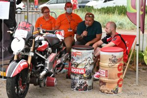 Na tle motocykla siedzi trzech ratowników medycznych i prowadzący imprezę dziennikarz z mikrofonem, fot. Michał Puszczewicz