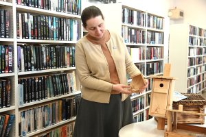 Kobieta w beżowym swetrze z karmnikiem w dłoni