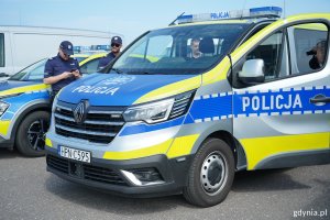 Policyjny radiowóz, a z tyłu stojący policjanci 