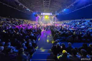 Hala Polsat Plus Arena Gdynia, widownia pełna ludzi, scena, niebieskie światło, kolorowe oświetlenie, grupa seniorów tańczy