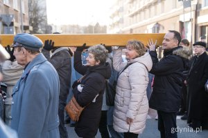 Uczestnicy Gdyńskiej Drogi Krzyżowej niosący krzyż. Wśród nich radny Dawid Biernacik