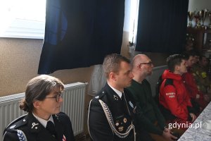 Mężczyźni i kobiety siedzący przy stole z białym obrusem i słuchający prelekcji