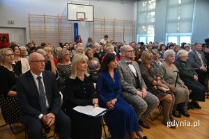 Kobiety i mężczyźni siedzący na krzesłach w szkolnej hali gimnastycznej