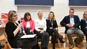 Grupa os&oacute;b, na pierwszym planie kobieta z mikrofonem