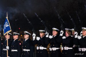 Szereg marynarzy Marynarki Wojennej strzela salwę z karabinów.