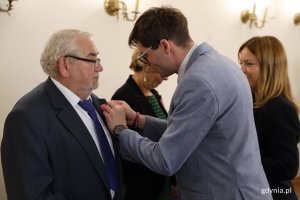 Mężczyzna w garniturze wręcza medal innemu mężczyźnie