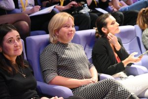 Kobiety siedzące na fioletowych fotelach w pierwszym rzędzie widowni