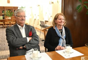 Mężczyzna w garniturze i kobieta z elegancką apaszką przy stole 