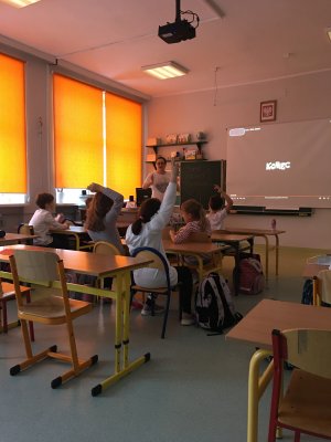 Prezentacja filmu o tolerancji w czasie lekacji, dzieci siedzą w ławkach, mają białe stroje.