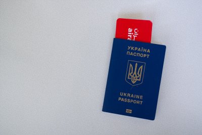 Blat stołu, na nim granatowy paszport Ukrainy. W paszporcie plastikowa karta