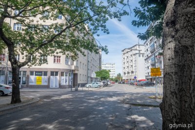 Ulica świętego Wojciecha w Gdyni. Widoczne drzewa, budynki, zaparkowane samochody. Letni dzień