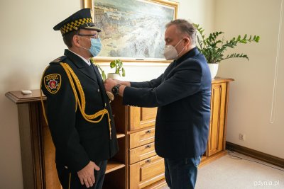 Wojciech Szczurek przypina Andrzejowi Bieniowi przypinkę do munduru służbowego