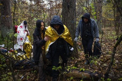 Aktywistka Grupy Granica pomaga uchodźcom z Syrii przejść z lasu do karetki grupy Medycy na granicy. Lipiny koło Hajnówki, 23.10.2021. Fot. Przemysław Kozłowski / Testigo Documentary