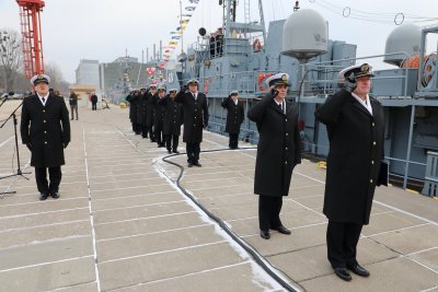 Nabrzeże. Widoczny okręt ORP Czajka, marynarze w mundurach stoją w rzędzie i salutują.