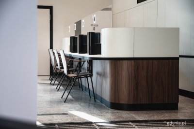 Sala obsługi urzędu miasta, widoczne stanowiska obsługi i krzesła