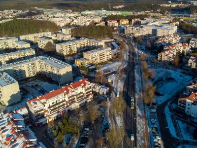 Zdjęcie lotnicze części dzielnicy Dąbrowa - widoczny fragment ulicy Rdestowej, budynki, bloki, sklepy i samochody. W tle obwodnica i sklep wielkopowierzchniowy na Karwinach
