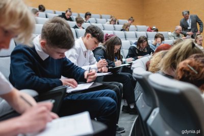 Sala audytoryjna w Muzem Marynarki Wojennej. Części foteli pusta, na części siedzi młodzież i pisze test na kartkach