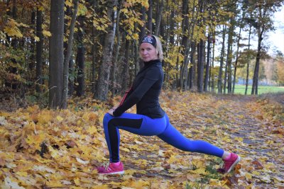 Wiola Czuryńska w stroju sportowym rozciąga się przed biegiem w lesie. Fot. Mariusz Czuryński