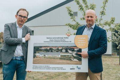 Wiceprezydent i wiceprzewodniczący z planszą informującą o żłobku.