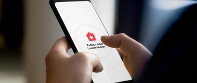 Telefon trzymany w rękach, na ekranie wyświetla się aplikacja 