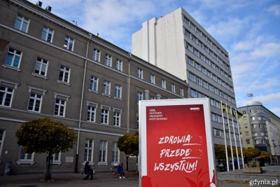 Widoczny fragmentu budynku Szpitala św. Wincentego a Paulo w Gdyni. Na górnej elewacji powstający neon, na pierwszym planie, z poziomu chodnika ekspozycja z okazji Święta Niepodległości z napisem 