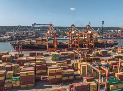 Terminal BCT, zdjęcie z drona, rzędy kontenerów, suwnice, statek handlowy, miasto w tle