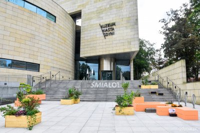 na zdjęciu frontowa fasada budynku Muzeum Miasta Gdyni z napisem Śmiało na schodach