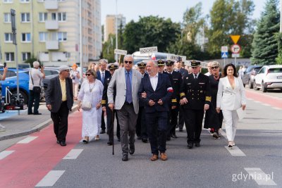 Starszy mężczyzna podtrzymywany przez innego mężczyznę w trakcie pochodu
