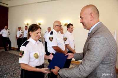 Emilia Borowczak przyjmuje z rąk Rafała Klajnerta, sekretarza miasta i dyrektora Urzędu Miasta Gdyni awans z aplikanta na młodszego strażnika. Fot. Przemysław Kozłowski