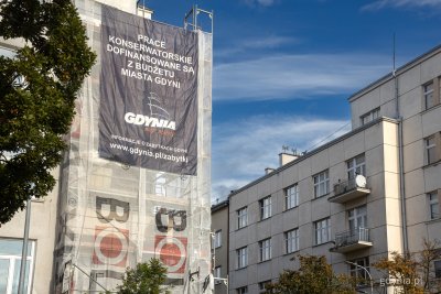 Gdynia, Śródmieście, widoczne fragmenty modernistycznych elewacji, na jednej z nich rusztowania i baner informujący o miejskiej dotacji