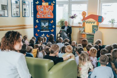 Prezydent z książką na fotelu, przed nim dzieci