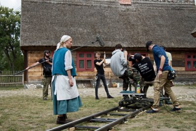 Plan filmowy w skansenie we Wdzydzach. Aktorka w ciąży, obok niej kilku filmowców i sprzęt.