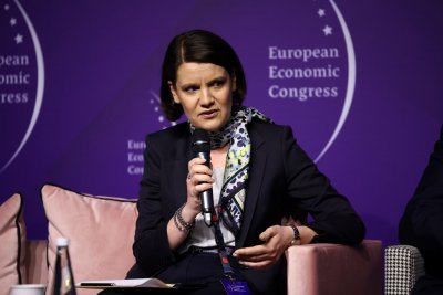 Katarzyna Gruszecka-Spychała siedzi na scenie. Za nią ciemnoniebieska ścianka z logotypem EEC